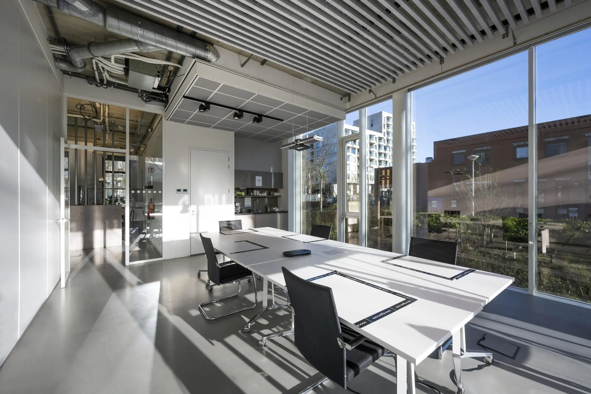 Vergaderruimte met moderne inrichting en grote ramen aan de Fred. Roeskestraat met uitzicht op kantoorpanden.